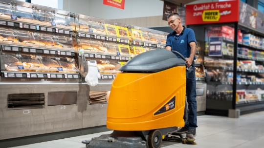Ein Mitarbeiter von ALDI Suisse putzt die Gänge der ALDI Suisse Filiale mit einem Gerät.