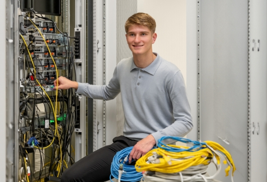Ein Mitarbeiter von ALDI Suisse steht am Server und repariert.