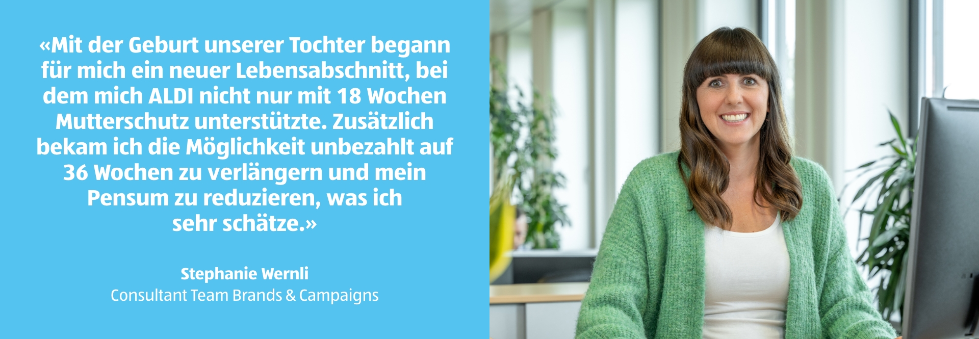 Eine Frau sitzt an ihrem Arbeitstisch und lächelt.