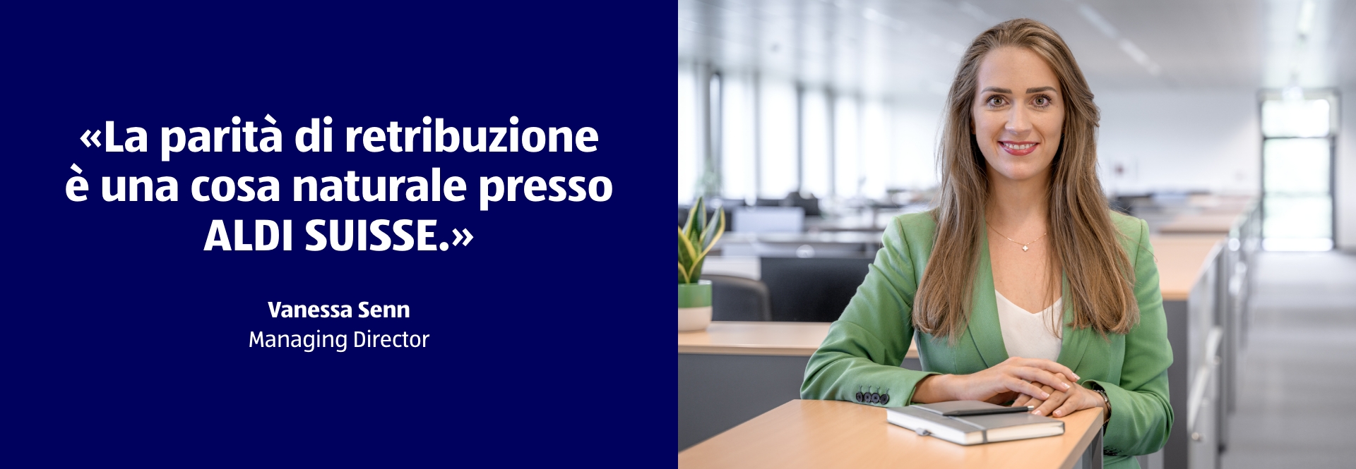 Una donna è in piedi alla scrivania e sorride. La didascalia della foto recita: La parità di retribuzione è una cosa naturale presso ALDI SUISSE